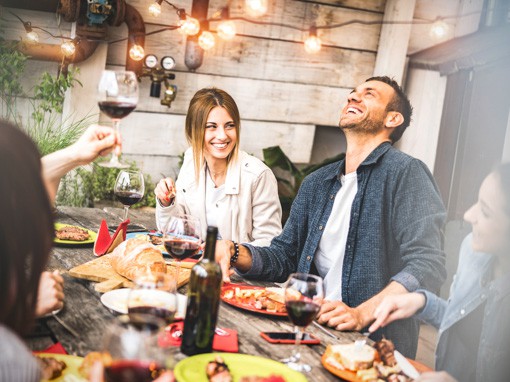 Ein Abendessen unter Freunden mit verschiedenen Gerichten und Wein zum Thema "7 Tipps zum Abnehmen ohne Diät"
