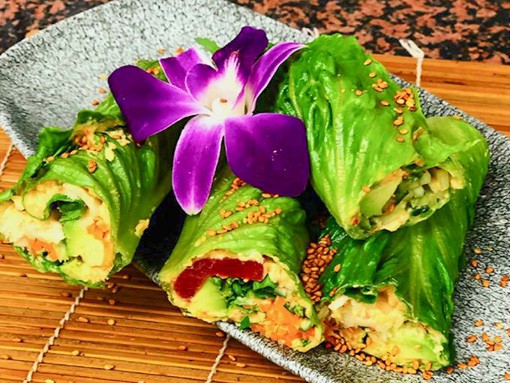 Das Gericht "Grüne Frühlings-Wraps" sehr schön angerichtet auf einem grauen Teller und mit einer Blüte dekoriert