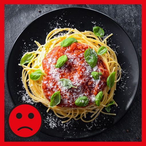 Ein Teller Spaghetti Bolognese mit einem roten traurigen Smiley